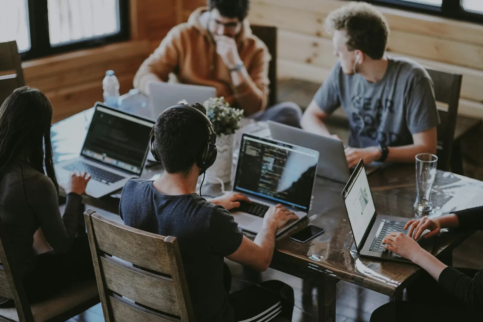 Small team working on laptops around a wooden table