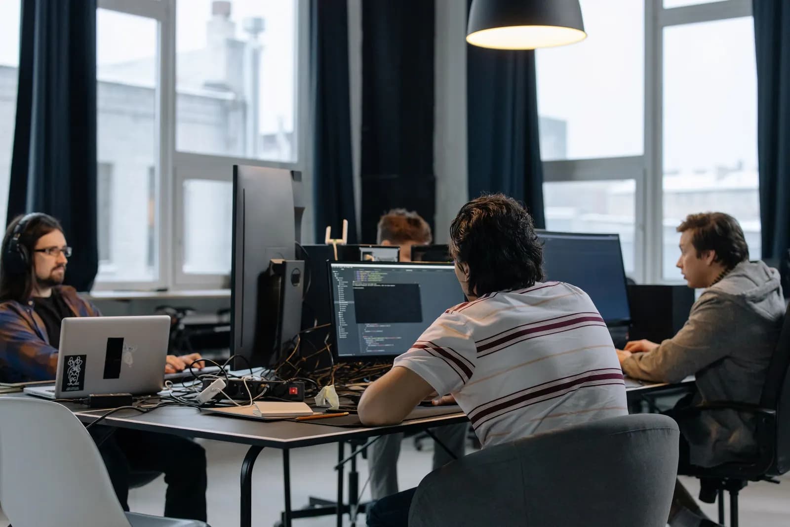 Developers working at computers in an office, one with code on his monitor