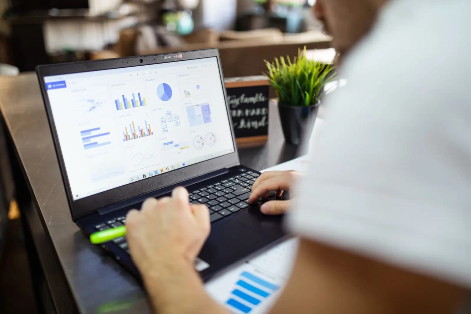 Person using a laptop showing a dashboard of charts and graphs
